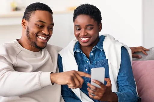 Two people smiling and learning together on a phone